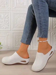 Close-up side view of white platform wedge clogs featuring elegant decorative cutouts