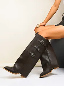 Close-up of retro dark brown trouser-leg boots with triple buckle detail and pointed toe.