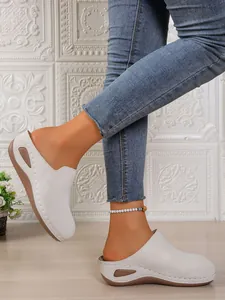 Side view of white closed-toe wedge slippers with platform sole and decorative cutout
