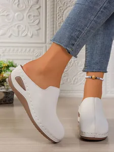 Detailed view of white platform wedge mules with decorative stitching and slip-on design.
