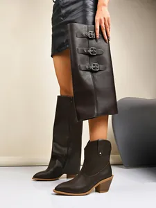 Detail view of brown western pant leg boots with adjustable metal buckles and pointed toe.