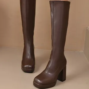 Close-up of brown faux leather knee-high boots with platform block heels and square toe