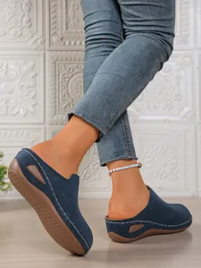 Close-up detail of navy blue women's wedge mules with white stitching and cutout design
