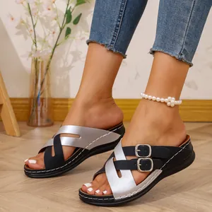 Close-up detail showing black and silver criss-cross straps on women's wedge sandals