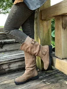 Detail view of taupe slouchy boots with buckle straps and knit cuffs