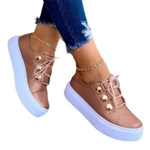 Sneakers platform da donna color oro rosa con bottoni metallici e suola bianca spessa.