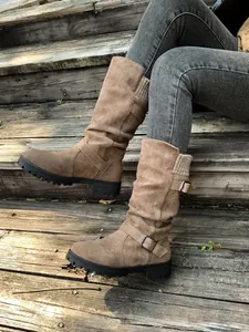 Detailed view of khaki suede mid-calf boots with buckle and knit trim on stairs