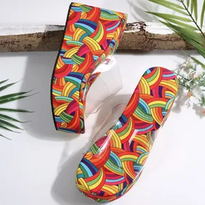Close-up of vibrant rainbow patterned thick-bottom wedge sandals with transparent plastic upper