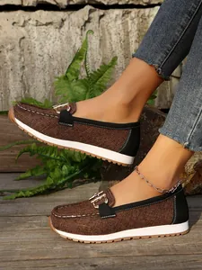 Detailed side view of brown textured women's loafers with metal buckle and thick white sole.