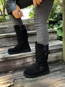 Detail view of black suede mid-calf boots featuring buckle straps and cozy knit cuffs