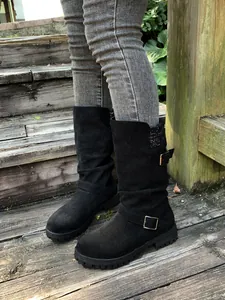 Close-up of black suede slouchy mid-calf boots with buckle straps and knit collars
