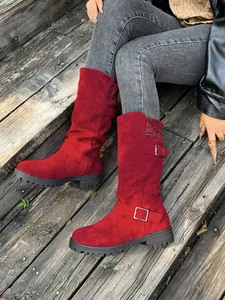 Detailed view of red suede mid-calf boots featuring stylish buckle straps and knit cuffs
