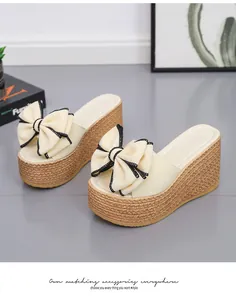 Detail view of beige platform wedge sandals with large decorative bow accents