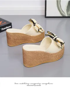 Detail of cream wedge slippers featuring a large bow and straw-woven platform sole