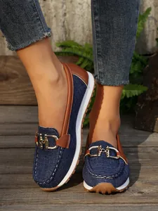 Detail of denim platform loafer with elegant gold metal buckle and brown trim.