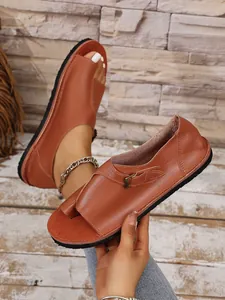 Nahaufnahme brauner Zehenstegsandalen aus Leder mit Schnalle und geschlossener Ferse