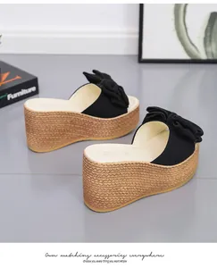 Close-up of black bow wedge sandals with woven platform texture and soft lighting