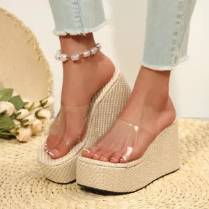 Close-up detail of straw-woven platform wedge sandals with clear transparent strap design.