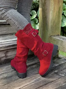 Detailed shot of stylish red faux suede mid-calf boots with buckle straps and a knitted collar.