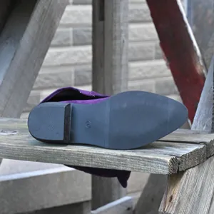Detailed macro view of anti-slip rubber sole and block heel on purple suede tall boots