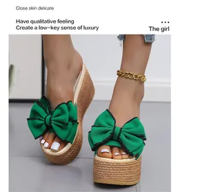 Close-up of stylish green wedge slippers with a large bow and woven platform sole.