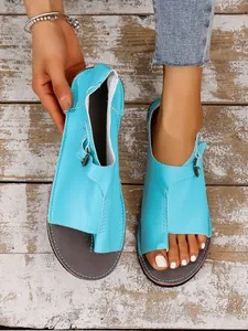 Detaillierte Nahaufnahme hellblauer Leder-Zehenringsandalen auf rustikalem Holzhintergrund.
