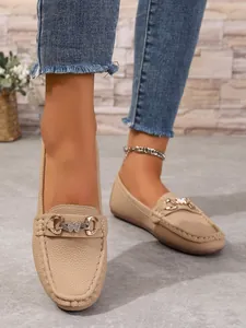 Detailed view of women's beige loafers with butterfly bit buckle and pebbled leather texture