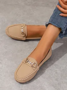 Close-up of beige loafers with decorative gold-toned butterfly metal buckle