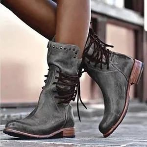 Close-up detail of vintage distressed grey leather boots featuring side lacing and studs