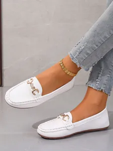 Stylish white soft leather loafers with gold buckle detail worn with casual denim.