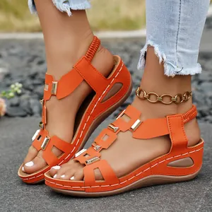Detailed view of orange peep toe wedge sandals with gold metal buckles and white stitching