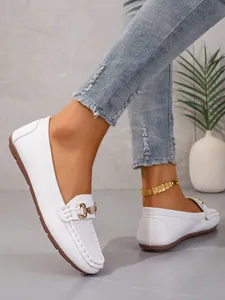 Close-up view of elegant white pebble-grain leather loafers with a gold metal buckle