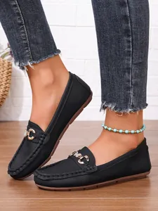 Close-up of black leather loafers with metal buckle on model's feet