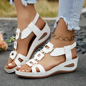 Close-up of white wedge sandals with gold buckles and elastic ankle straps for women