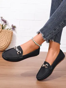 Detailed view of women's black casual loafers with metal buckle decoration and soft sole