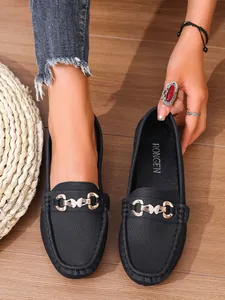 Close-up of elegant black textured leather loafers with golden butterfly metal buckle