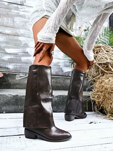Macro detail of dark brown pant-leg boots featuring pointed toe and chunky block heel