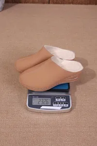 Pantoufles beiges doublées de polaire sur une balance pesant environ 232,6 grammes