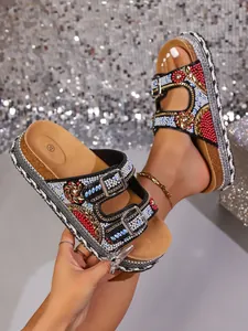 Detail van luxe plateausandalen met strassteentjes, dubbele gespen en gevlochten zool