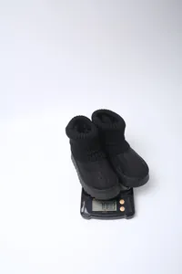 Detail shot of black platform snow boots with knit cuffs being weighed on a scale