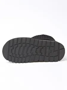 Detail showing non-slip rubber outsole design on black knitted cuff snow boots