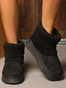 Detailed view of black platform snow boots with a ribbed knit collar and plush lining.