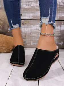 Gros plan de mules en daim noir avec coutures contrastées et doublure en fourrure chaude