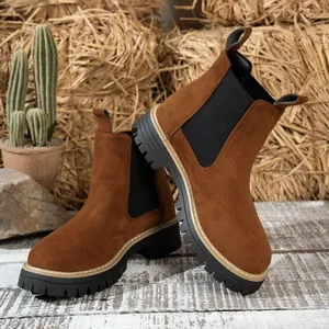 Detalle de botines Chelsea de ante marrón con suelas de plataforma negras gruesas.