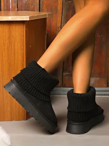 Detail view of black platform snow boots with warm knitted ribbed cuffs for winter.