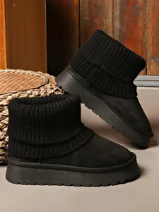 Close-up detail of black winter snow boots featuring platform soles and knitted ribbed cuffs