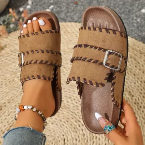 Women's brown platform slide sandals with buckle straps and braided trim on woven mat.