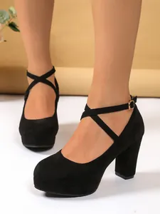 Dettaglio scarpe col tacco alto in camoscio nero con eleganti cinturini incrociati alla caviglia