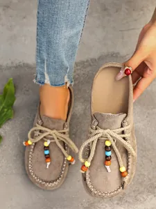 Close-up of suede platform mules featuring colorful beaded laces and contrast stitching