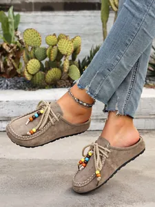 Detailed view of women's taupe suede mules featuring colorful decorative bead accents